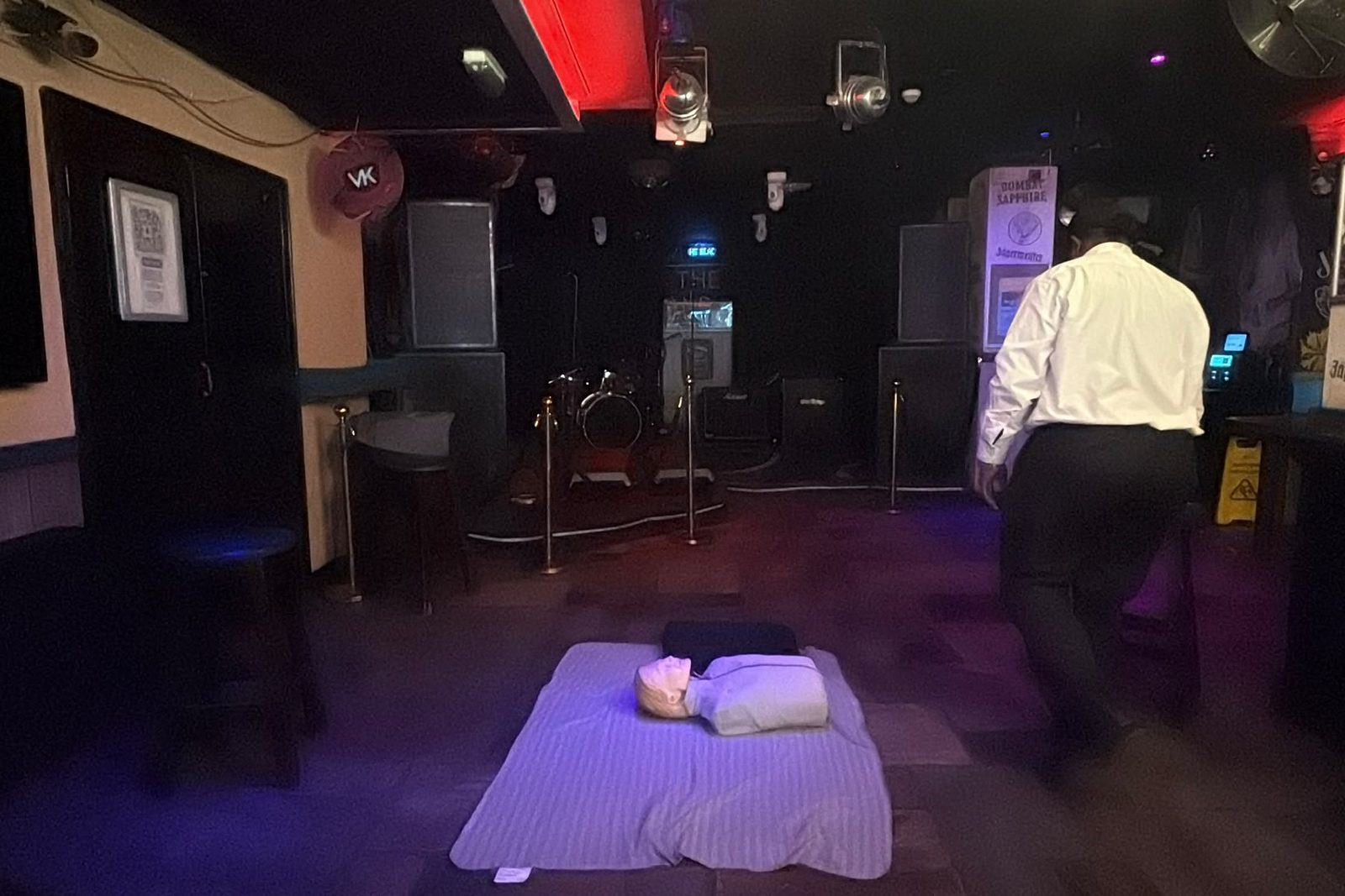 A resuscitation manikin laid out on a mat in an empty venue before a first aid session.