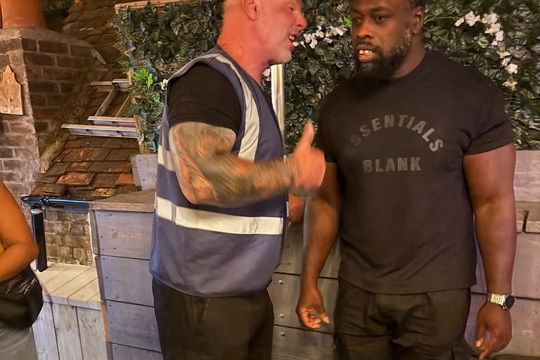 A supervisor in a high visibility vest talking with a colleague outside a venue.