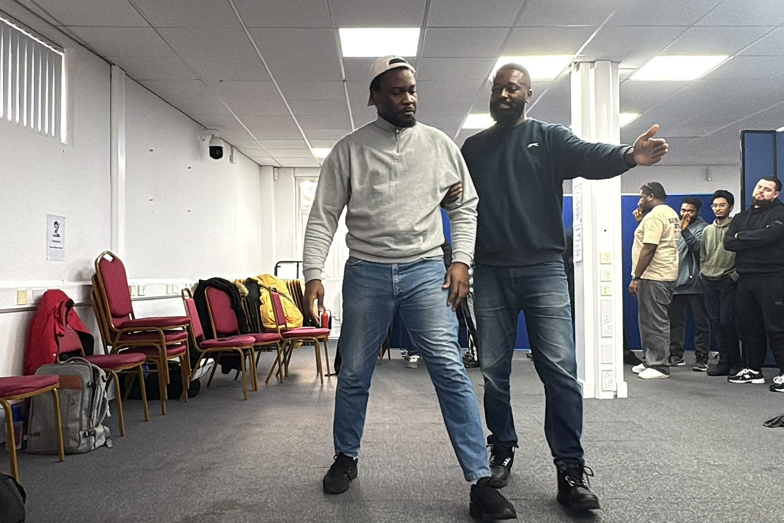 A trainer demonstrating a controlled escort technique while the class watches.