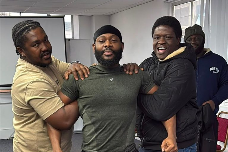 Three learners celebrating together in the training room at the end of their course.