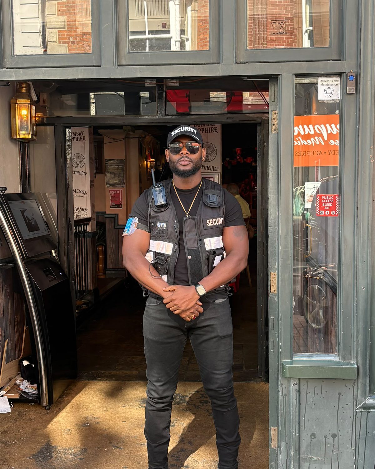 A door supervisor in a high visibility vest standing at a venue doorway.