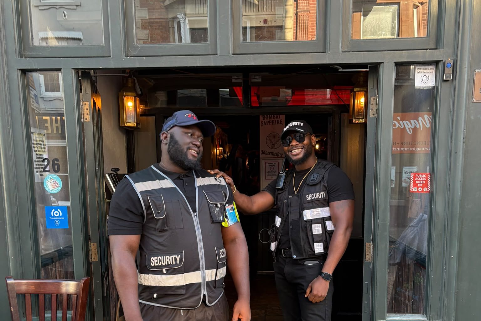Two door supervisors talking in the doorway of the venue they are working.