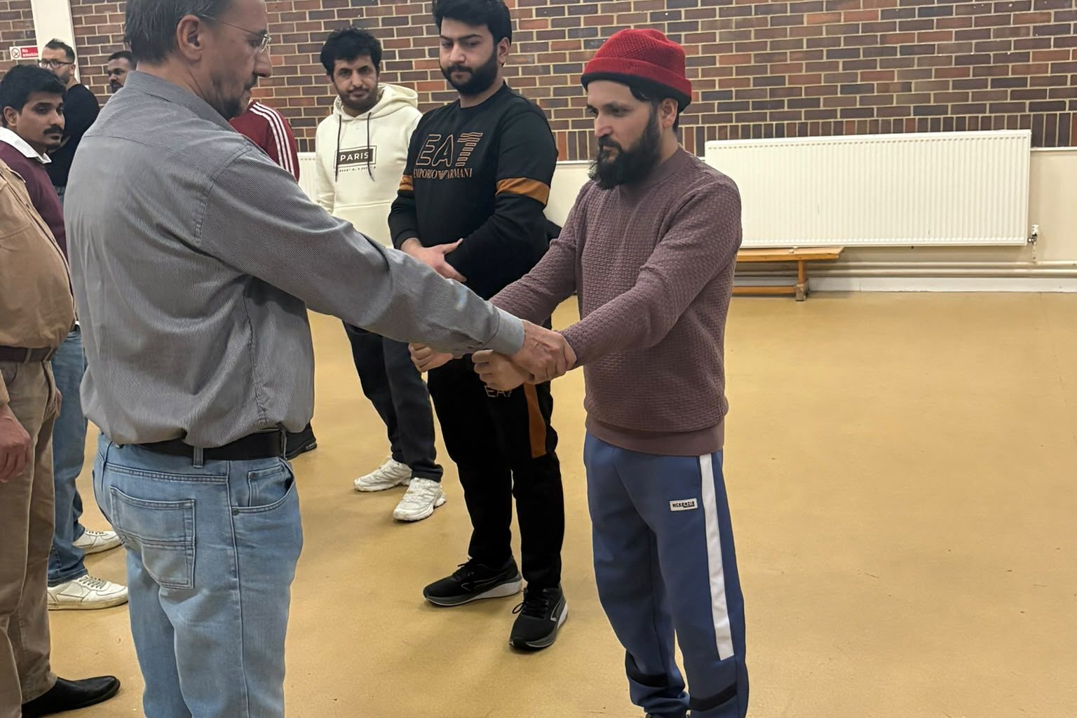 Two learners practising a wrist release while the trainer supervises.